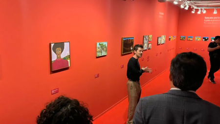 Curador da exposição "Sofrência" explicando obras no evento de abertura