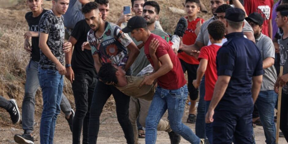  Homem ferido sendo carregado por manifestantes ao longo da cerca fronteiriça com Israel na Faixa de Gaza