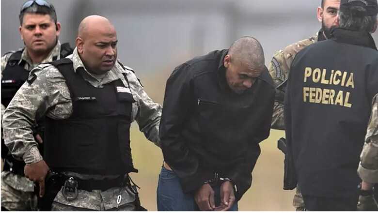 Ad&eacute;lio Bispo de Oliveira sendo escoltado por policiais federais em aeroporto de Juiz de Fora