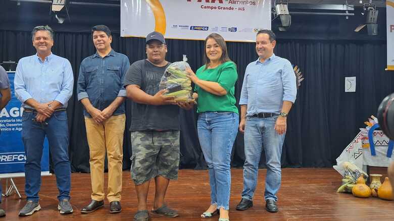 O indígena Dirceu da Aldeia Nova Canaã recebendo a cesta das mãos da prefeita Adriane Lopes ao lado de autoridades