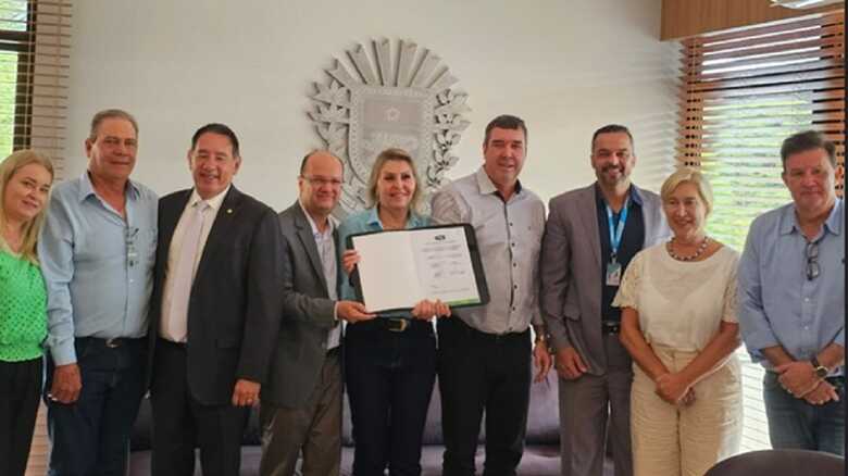 A prefeita de Douradina, Nair Branti, exibe o contrato. À direita o governador do MS, Eduardo Riedel e o superintendente em exercício da CAIXA, Thiago Quintas