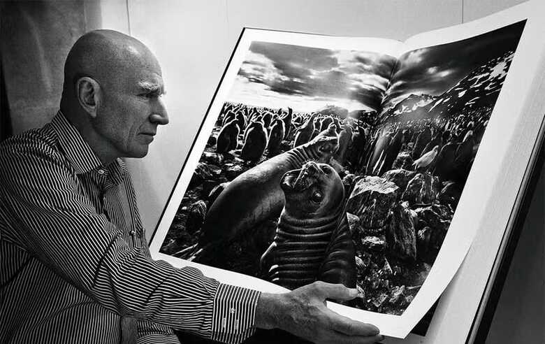 Sebastião Salgado ao lado de uma das fotografias 