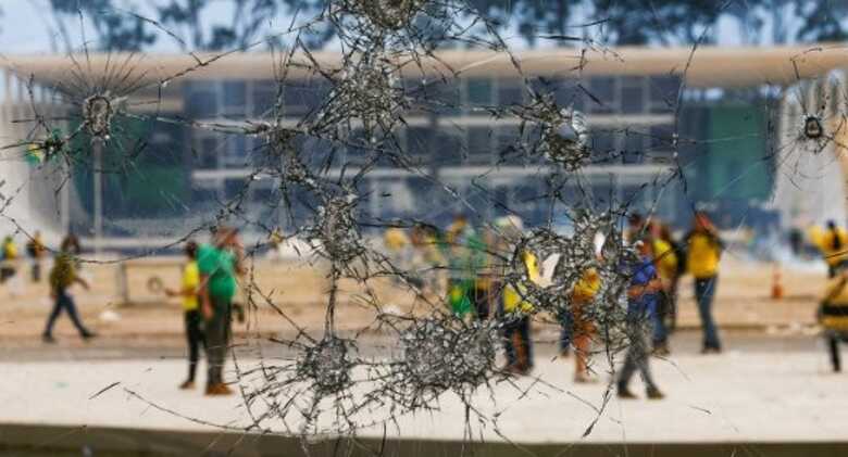 Manifestantes através de vidros quebrados no atentado golpista