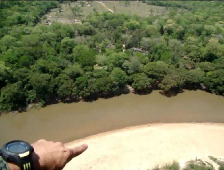 Policial aponta onde estava instalada a tirolesa, na margem do rio que separa o Brasil do Paraguai
