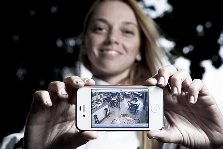 A chef Nicoli Geigner mostra no celular imagens de câmeras de vigilância de seu restaurante, em São Paulo