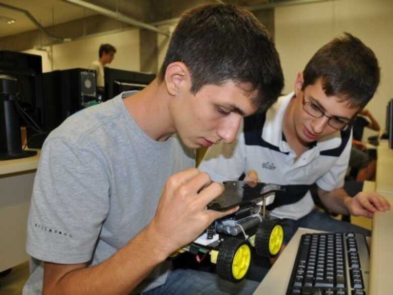 Estudantes do Colégio Militar mexendo no robô criado por eles.