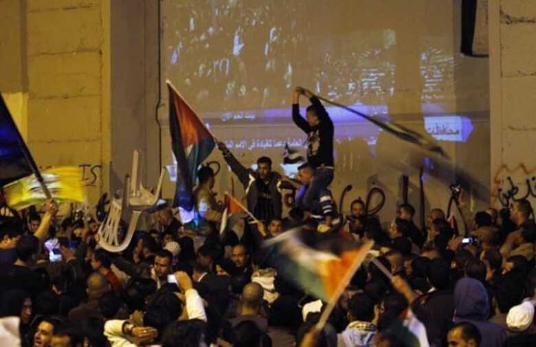 Palestinos celebram em Belém, na Cisjordânia, próximo à barreira de separação com Israel, a vitória diplomática desta quinta-feira (29).