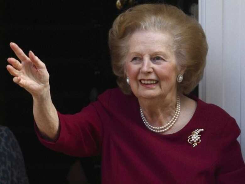 A ex-premiê britânica Margaret Thatcher acena da entrada de sua casa em 2010.