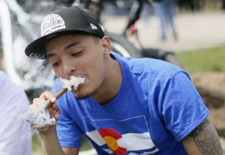 Homem fuma maconha em manifestação pró-maconha neste sábado na cidade de Denver.