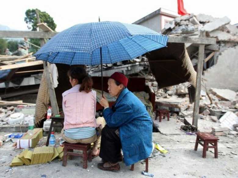 População acompanha resgate de vítimas ao lado de um edifício Sichuan.