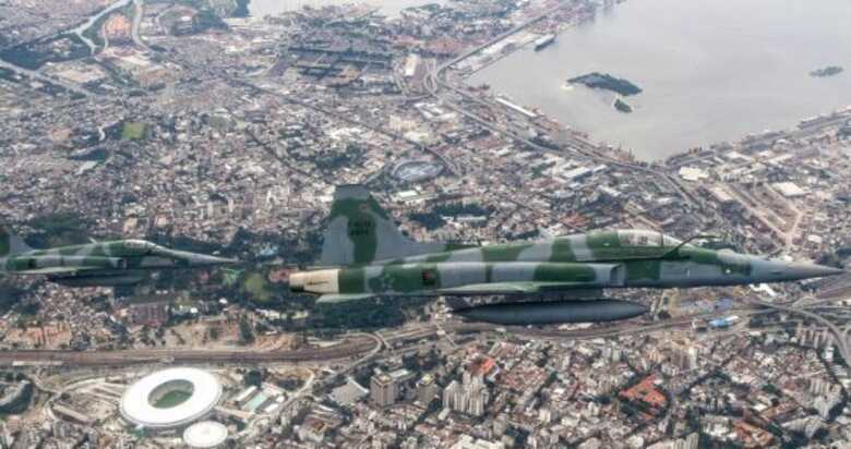 No céu do Rio de Janeiro, dois caças F5M se aproximam de aeronave não identificada para dominar a situação, em exercício da FAB.