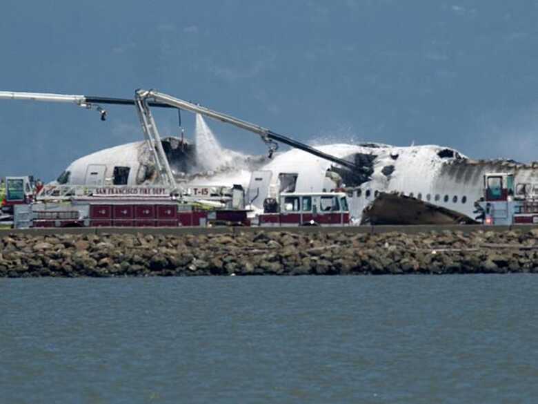 Caminhão dos Bombeiros despeja água na aeronave, que pegou fogo após o pouso. (Foto: AP)