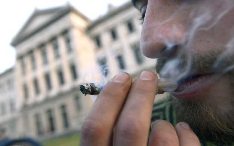 Homem fuma maconha do lado de fora do Congresso, onde deputados debateram legalização da venda da maconha (31/7). (Foto: AP)