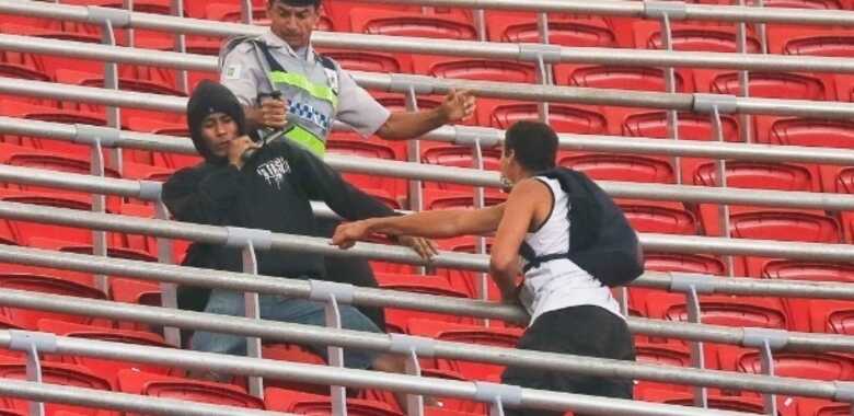 Policial tenta evitar briga entre torcedores na partida entre Corinthians e Vasco, no estádio Mané Garrincha. (Sergio Lima/Folhapress)