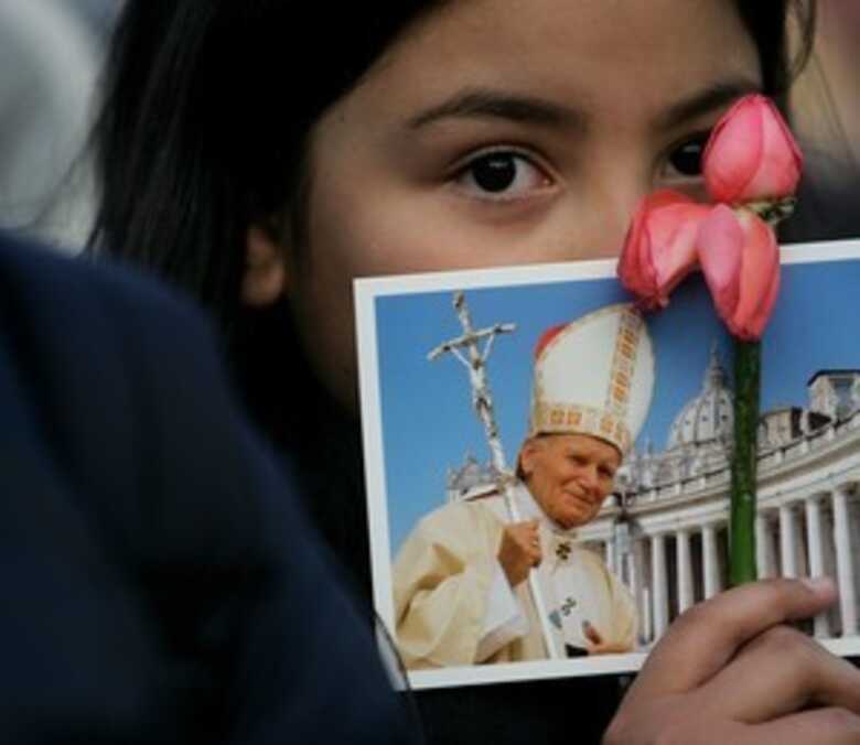 Garota segura cart&atilde;o com a imagem de Jo&atilde;o Paulo II. (Foto: Getty Images)