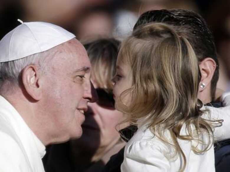 Papa interage com criança antes de sua audiência semanal na Praça São Pedro nessa quarta. (Foto: AP)