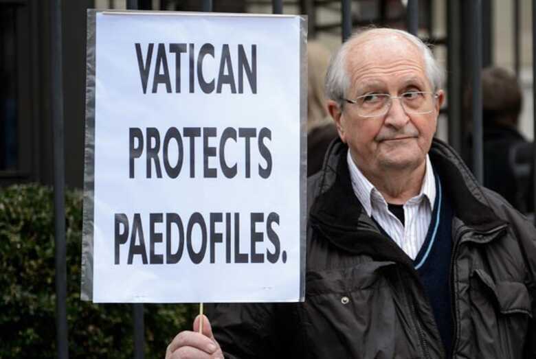 Homem protesta nesta quinta-feira (16) contra a Santa Sé. 'O Vaticano protege pedófilos', diz o cartaz. (Foto: Fabrice Coffrini/AFP)