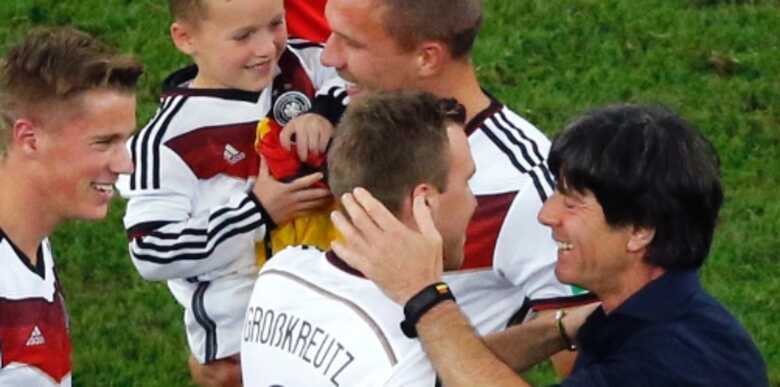 Podolski leva o filho no campo para comemorar o título da Alemanha, junto com o técnico Joachim Löw e Kevin Grosskreutz. (Foto: Reuters/Fabrizio Bensch)