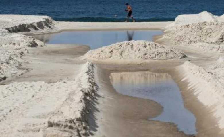 Homem chuta bola enquanto sistema de esgoto flui na praia de Copacabana, no Rio de Janeiro