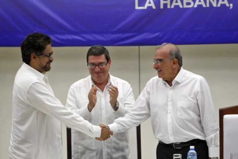 O n&uacute;mero dois das Farcs, Luciano Mar&iacute;n, tamb&eacute;m conhecido como Iv&aacute;n M&aacute;rquez, e o ex-vice-presidente da Col&ocirc;mbia, Humberto de la Calle, apertam as m&atilde;os ap&oacute;s assinar acordo hist&oacute;rico em Havana