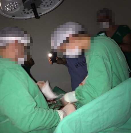 Médicos realizando uma cirurgia com a lanterna de celular