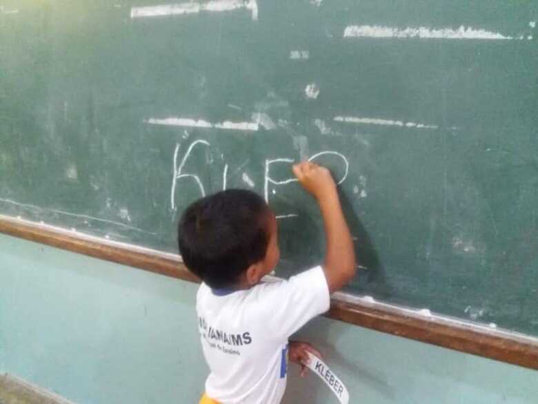 Klebinho escrevendo seu nome na escola