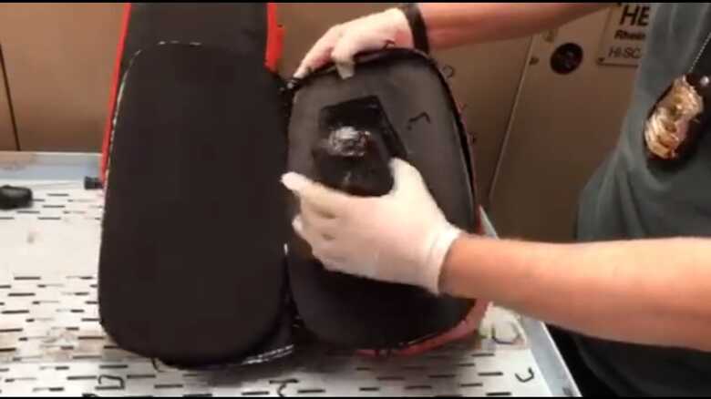 Polícial federal retirando arma de dentro de um equipamento de luta