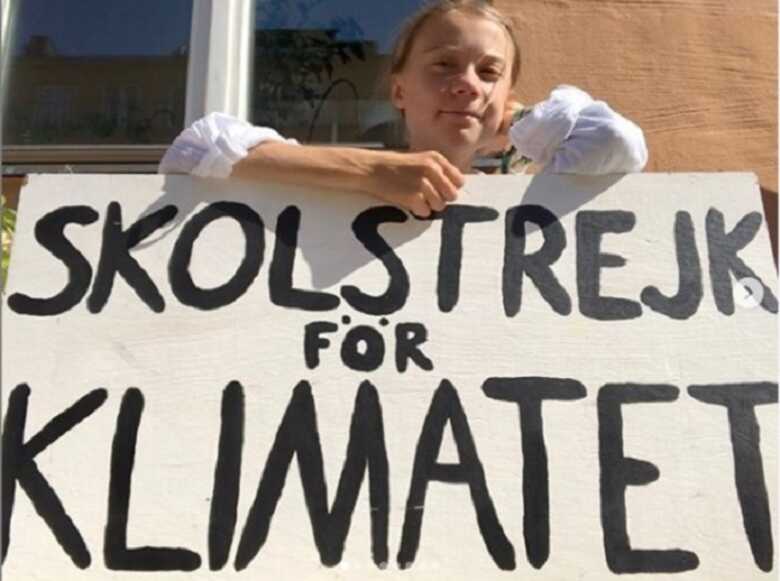 Greta Thunberg, com um cartaz onde diz 'Greve escolar pelo clima' em protesto por mudanças políticas contra o aquecimento global