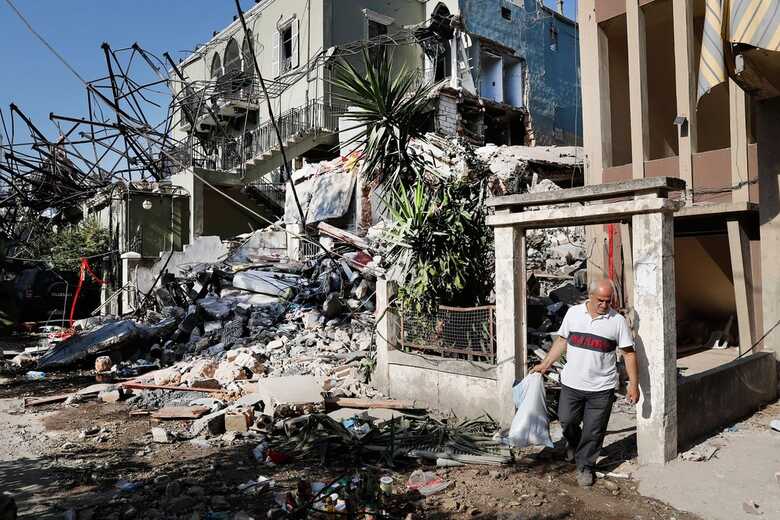 Homem carrega nesta quinta (6) seus pertences ao sair de sua casa destruída por explosão no porto de Beirute